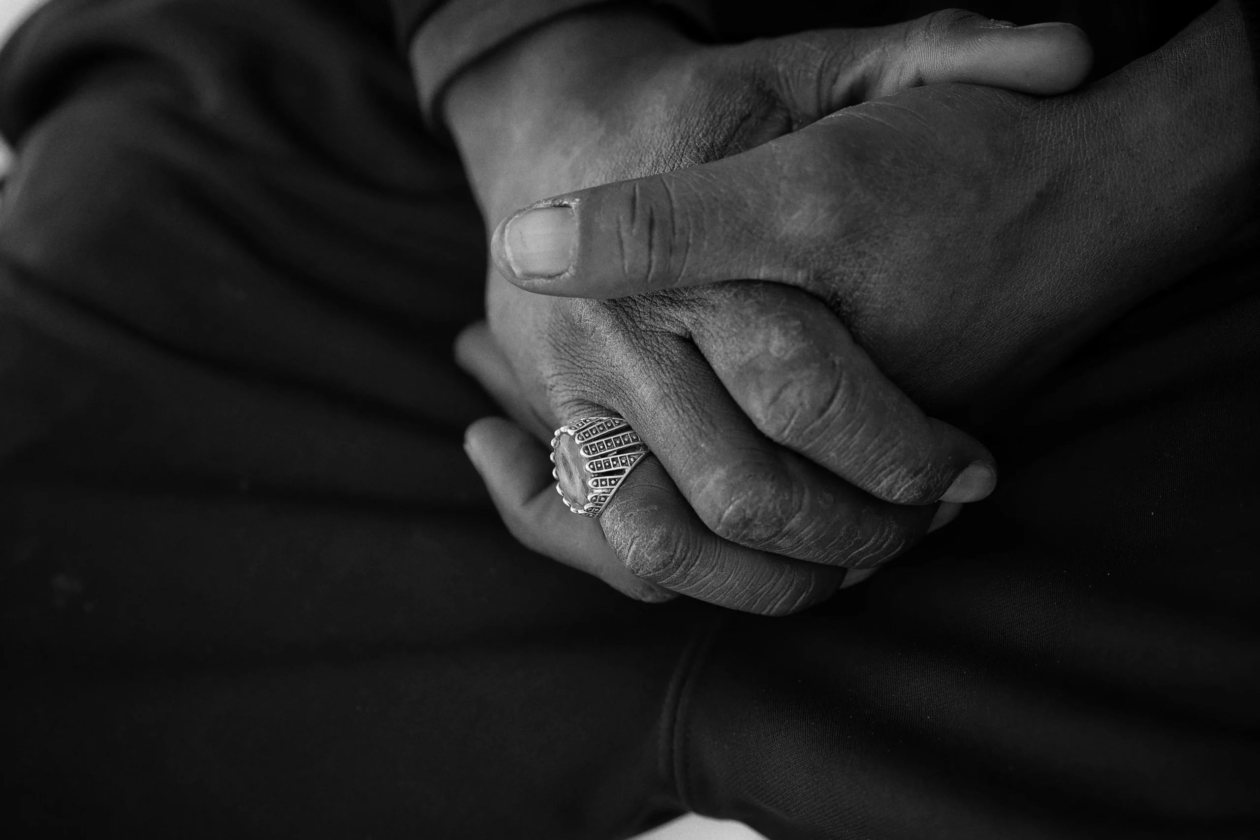 To hænder holdt sammen, den ene bærer en bred sølvring med struktureret overflade